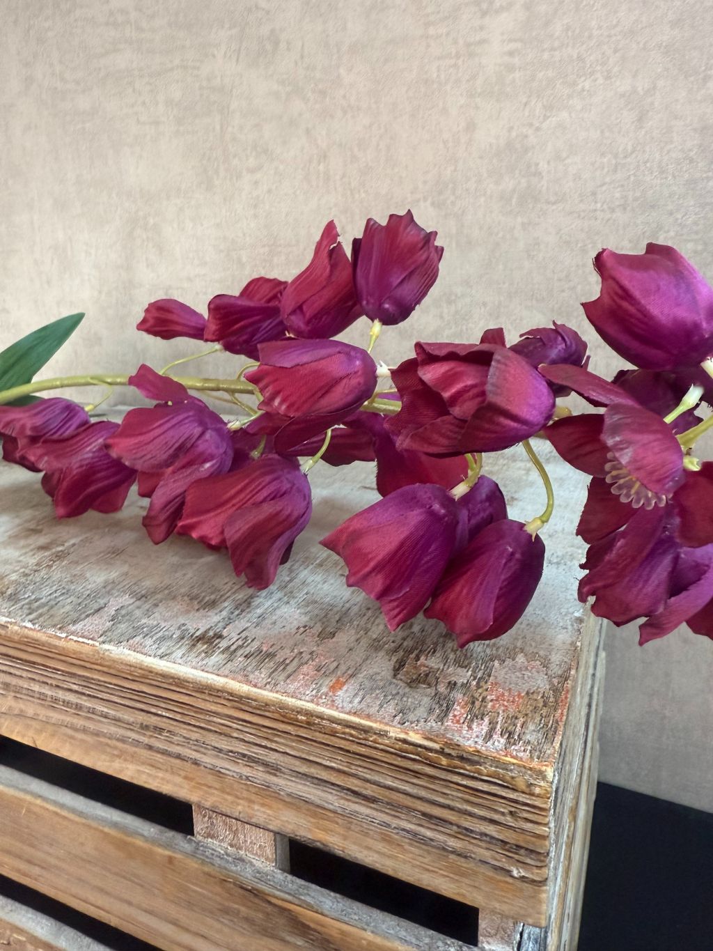 Kunstbloem Campanula in bordeaux rood met belvormige bloemen en lange steel van 92 cm op een houten kist