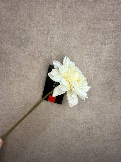 Crème-witte kunst dahlia van Colmore met korte steel, liggend op een lichtgrijze ondergrond met zichtbaar etiket.