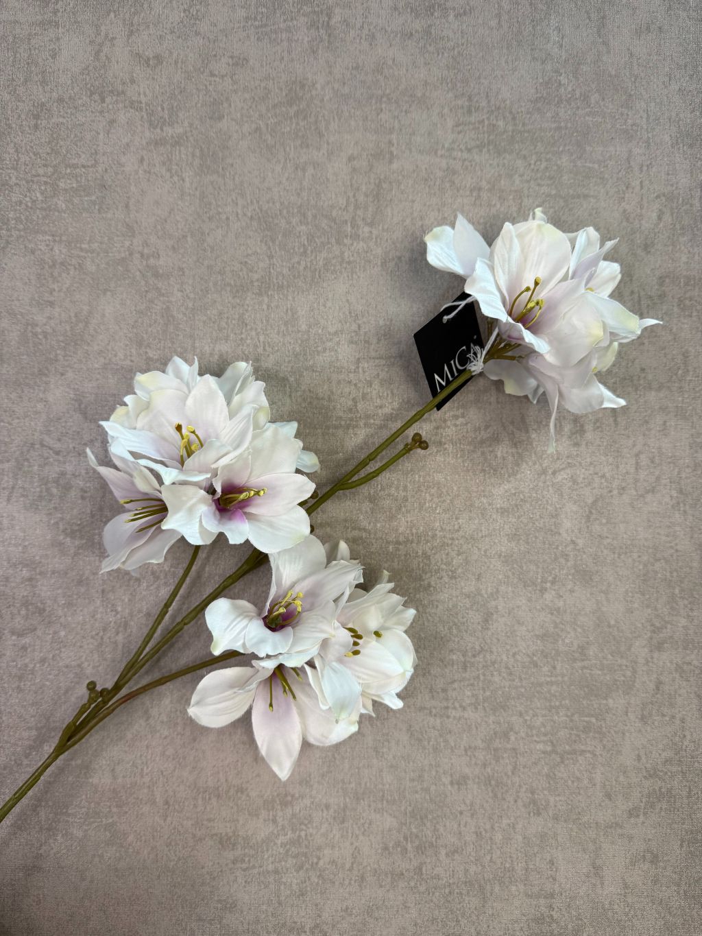 Kunstmatige hibiscus bloem in crème roze tinten met meerdere bloesems op een steel tegen een neutrale achtergrond.