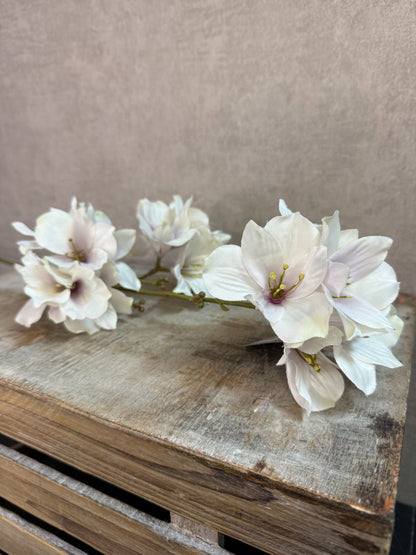 Kunstmatige hibiscus bloem in crème roze tinten met meerdere bloesems op een steel tegen een neutrale achtergrond.