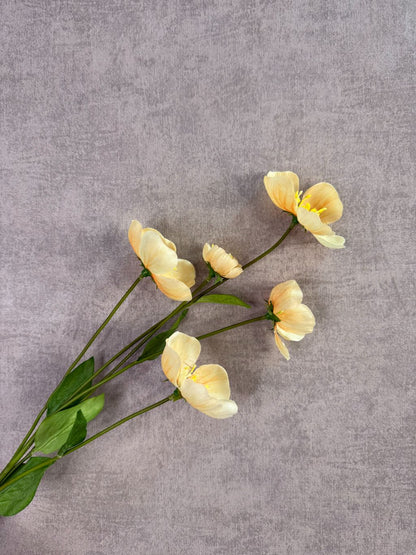 Kunstbloem Melastoma met zachte gele bloemen en groene bladeren tegen een neutrale achtergrond.