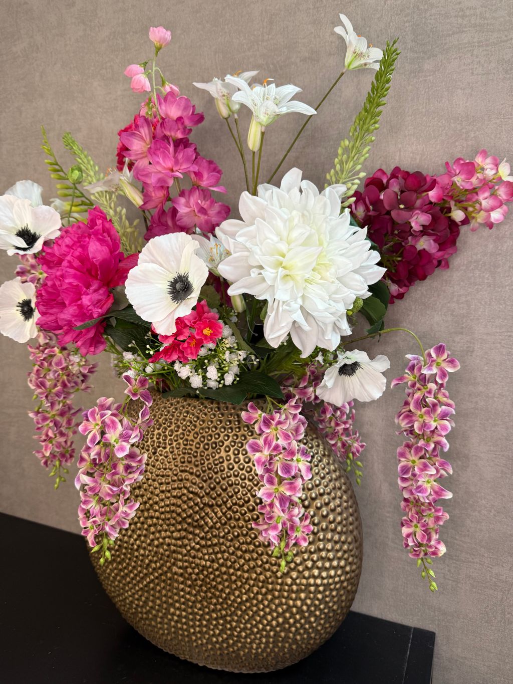 Groot kunstboeket met roze en witte bloemen in een ronde goudkleurige vaas.