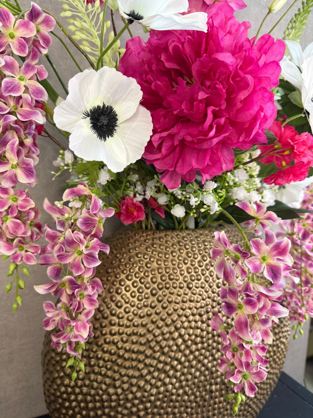 Groot kunstboeket met roze en witte bloemen in een ronde goudkleurige vaas.