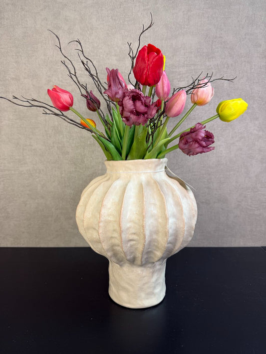 Kleurrijk kunstboeket met tulpen en decoratieve takken in een lichte vaas, vrolijke uitstraling en realistische afwerking.