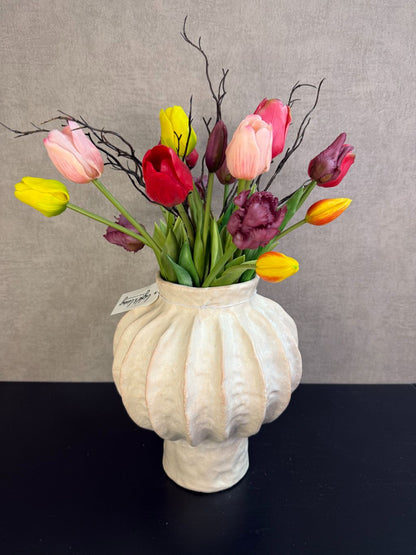 Kleurrijk kunstboeket met tulpen en decoratieve takken in een lichte vaas, vrolijke uitstraling en realistische afwerking.