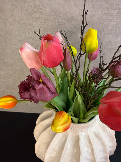 Kleurrijk kunstboeket met tulpen en decoratieve takken in een lichte vaas, vrolijke uitstraling en realistische afwerking.