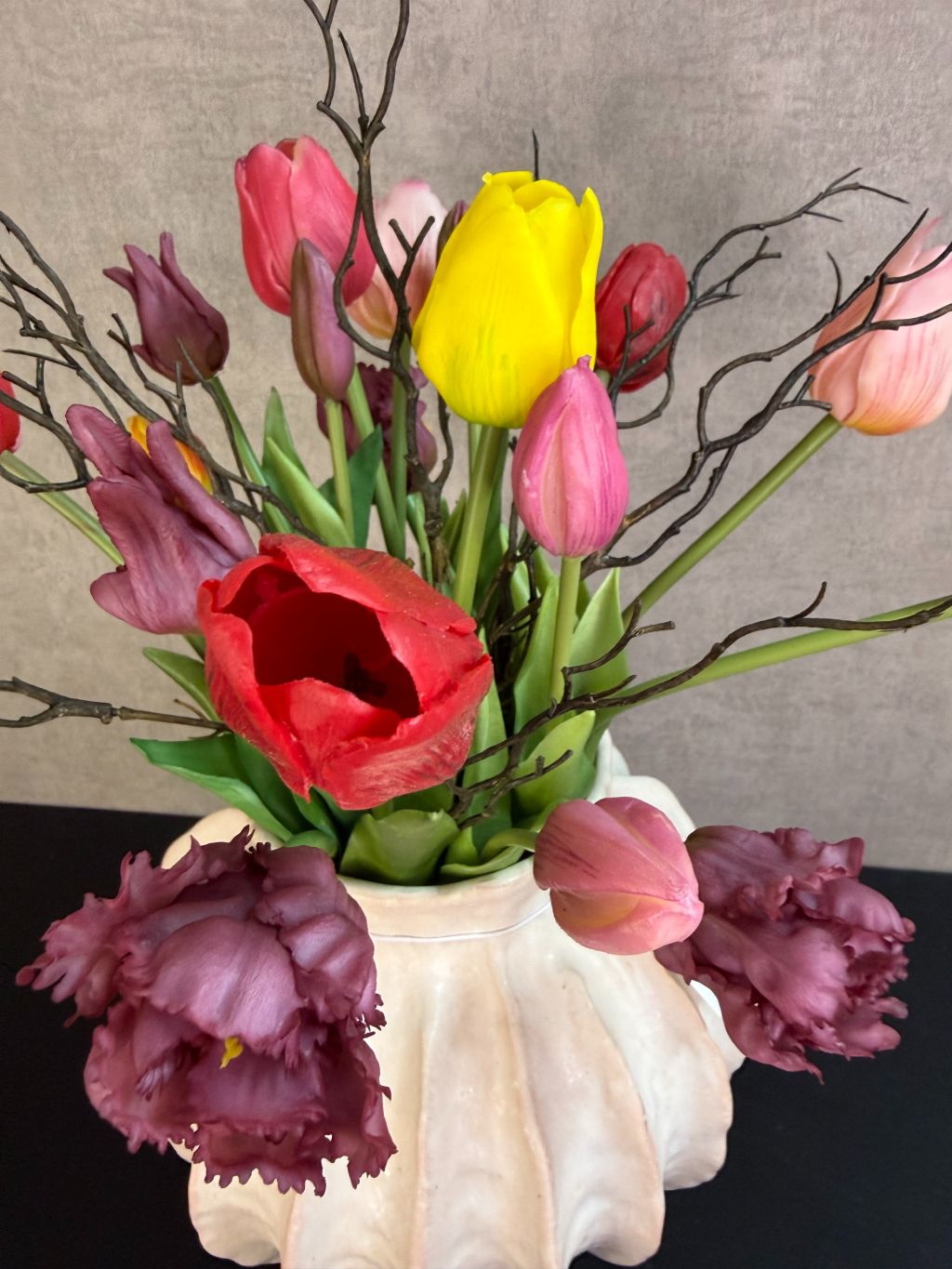 Kleurrijk kunstboeket met tulpen en decoratieve takken in een lichte vaas, vrolijke uitstraling en realistische afwerking.