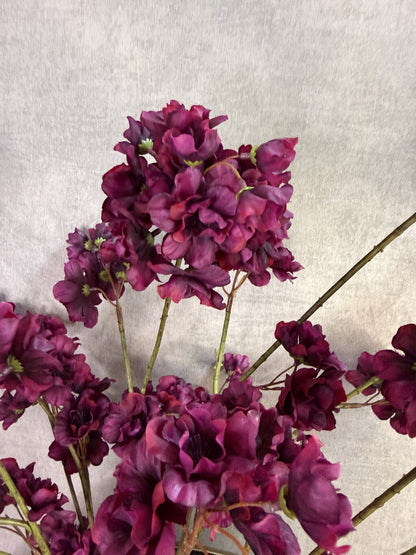 Kunstboeket Prunus in aubergine kleur in een grote ronde vaas met reliëf.