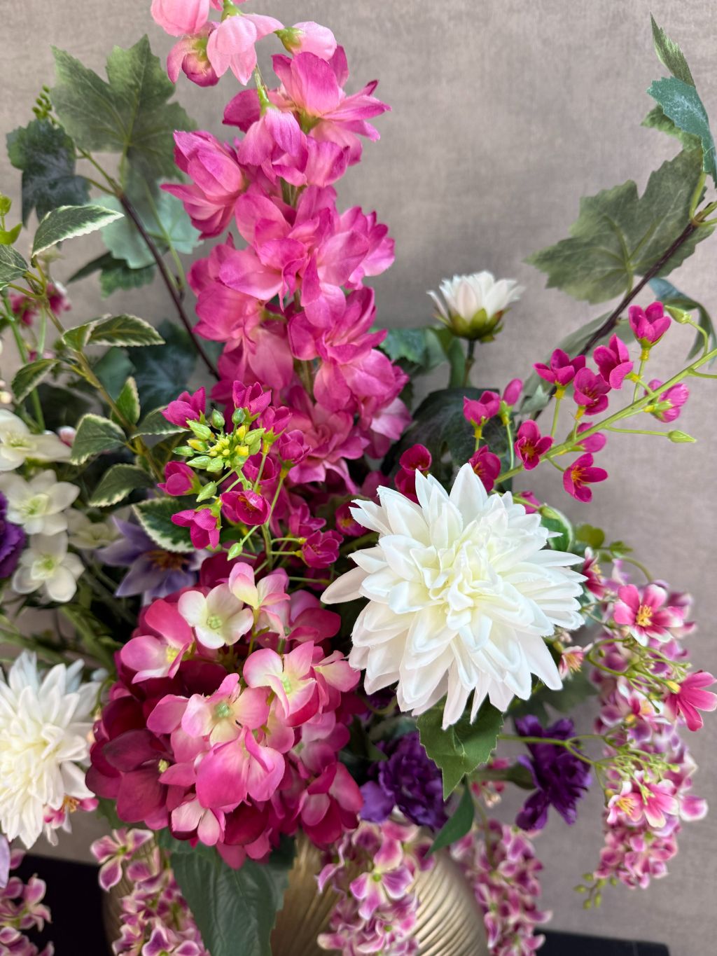 Groot kunstboeket Rosa in roze, paars en wit tinten met groene bladeren, geplaatst in een ronde goudkleurige vaas.