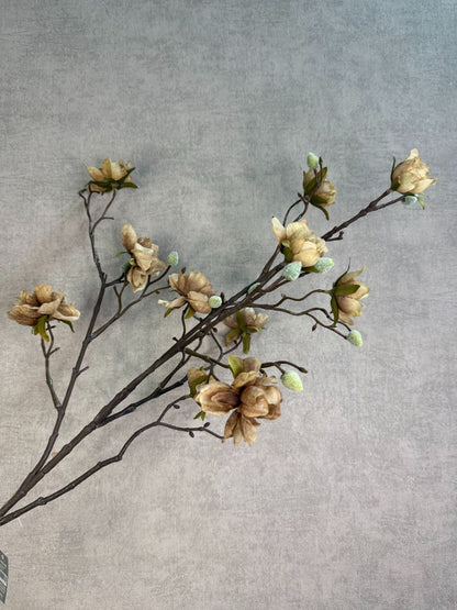 Lichtbruine kunsttak met bloesems en vertakte structuur tegen een neutrale achtergrond