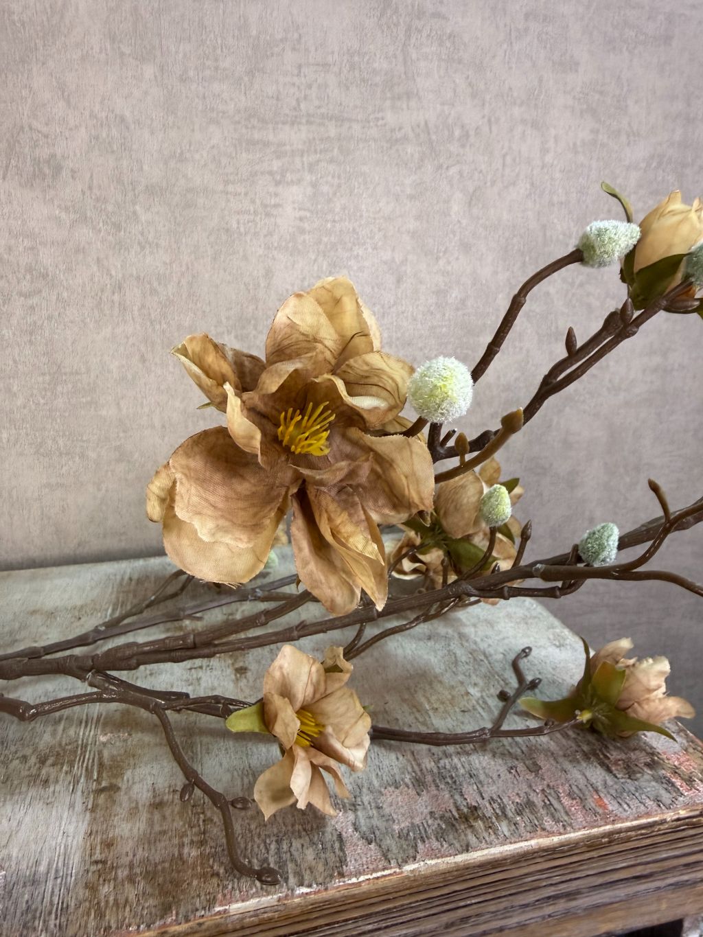 Lichtbruine kunsttak met bloesems en vertakte structuur tegen een neutrale achtergrond