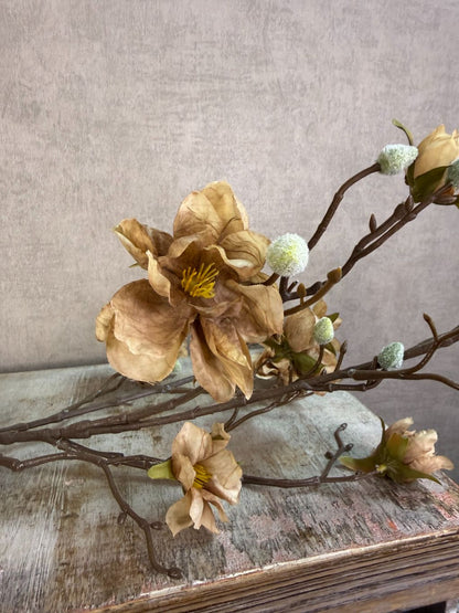 Lichtbruine kunsttak met bloesems en vertakte structuur tegen een neutrale achtergrond