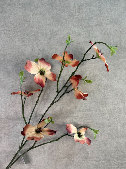 Kunsttak met bruine en crème bloesems en groene knoppen tegen een neutrale achtergrond.