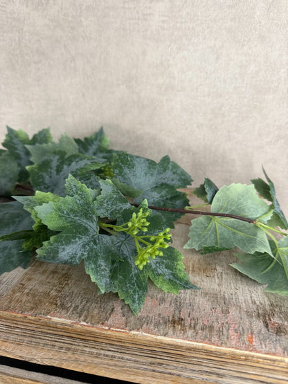 Kunsttak druivenblad van 77 cm met grote groene bladeren en fijne details op houten ondergrond