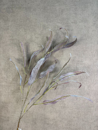 Paarse kunsttak eucalyptus met slanke bladeren en subtiele glitter tegen een neutrale achtergrond.