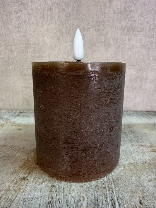 Bruine led kaars met realistische vlam op een houten ondergrond.