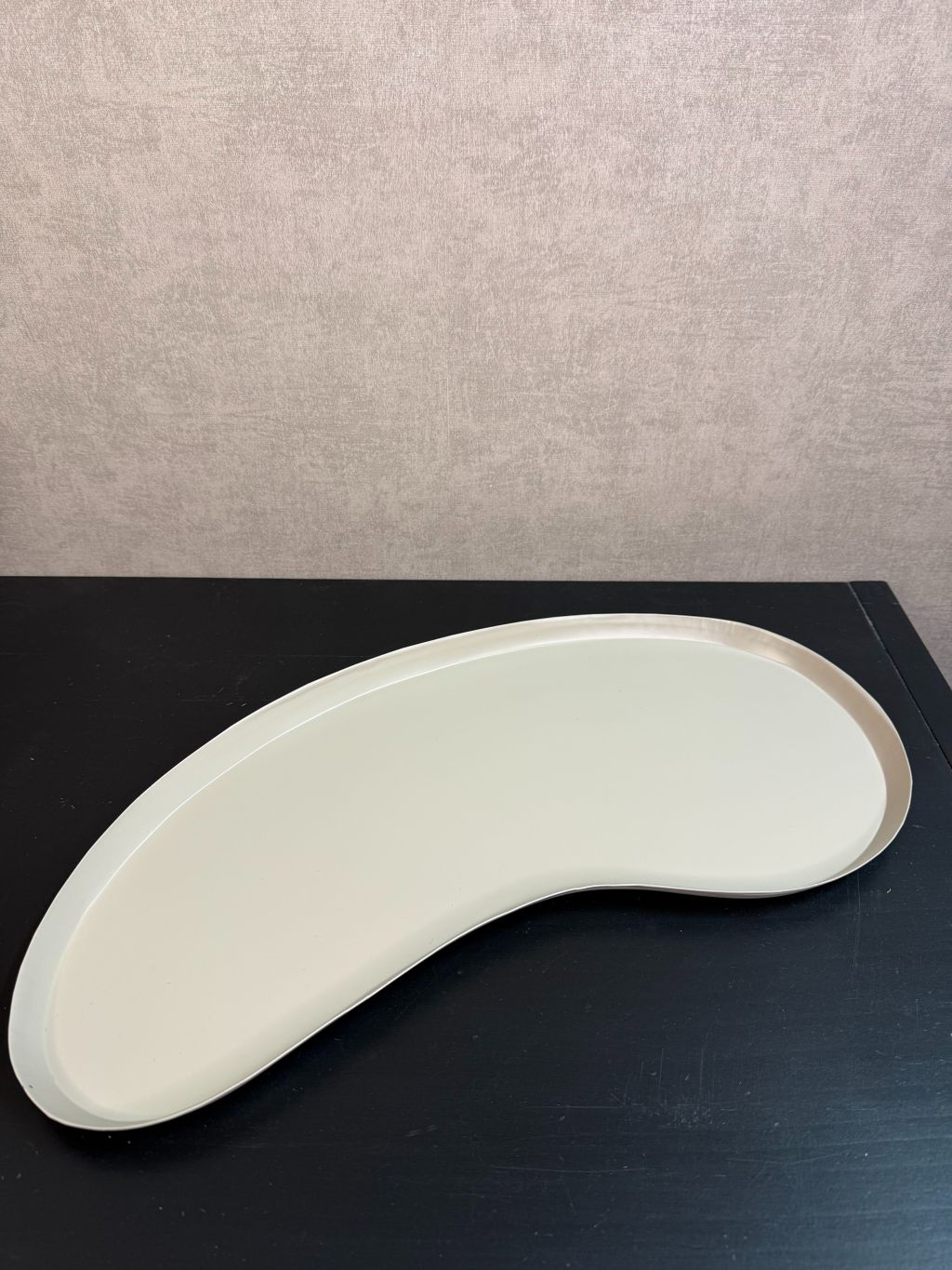 Organisch gevormd beige metalen dienblad met moderne kidney-vorm.
