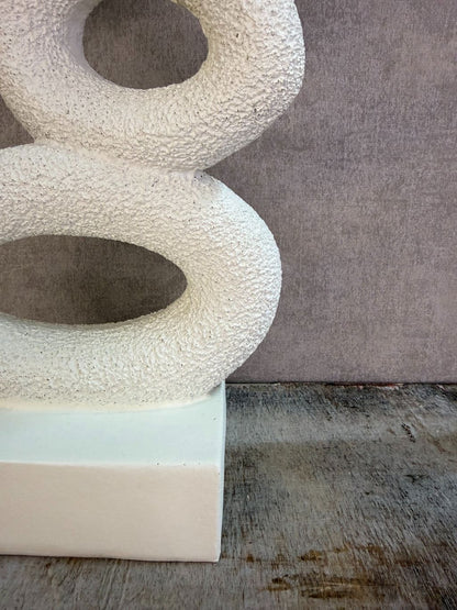 Beige abstract ornament met organische vormen op een rechthoekige voet.