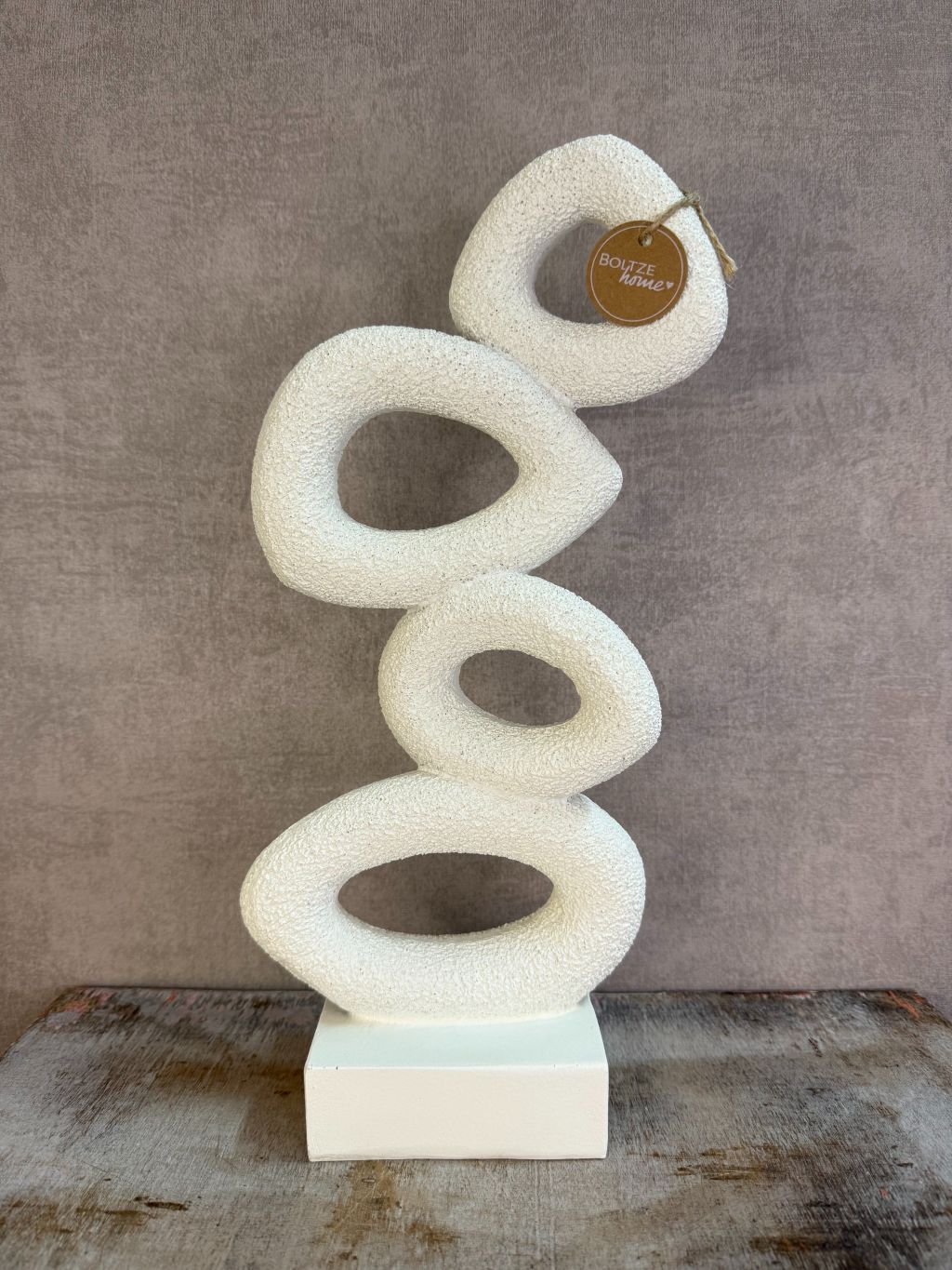 Beige abstract ornament met organische vormen op een rechthoekige voet.