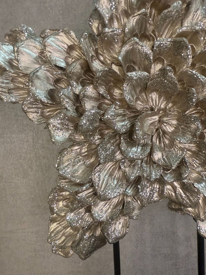 Ornament Ster glitter champagne – decoratieve ster met glanzende bloemvormige blaadjes op zwarte standaard.