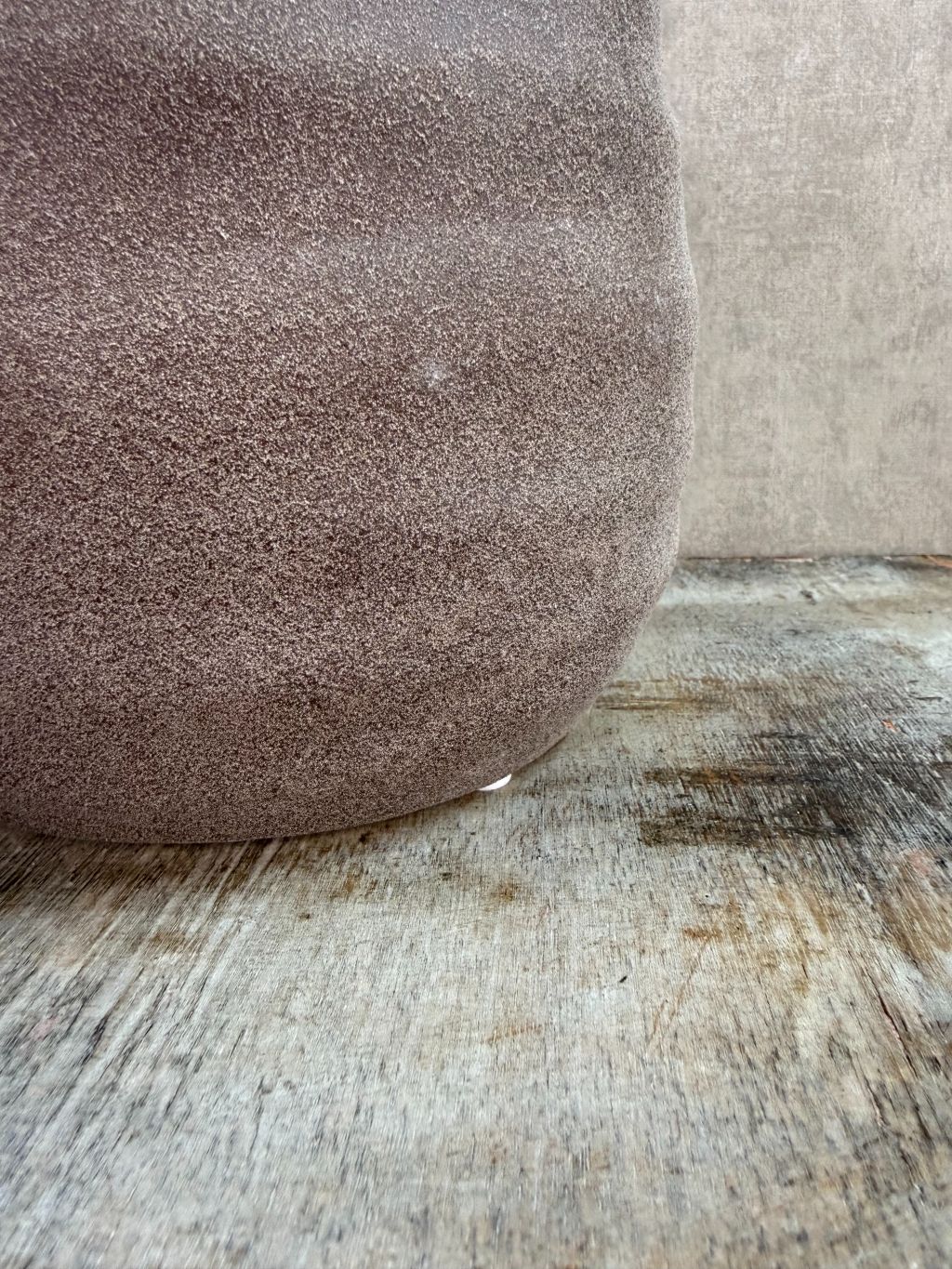 Ronde bruine keramieken plantenpot met matte structuur op een houten ondergrond.