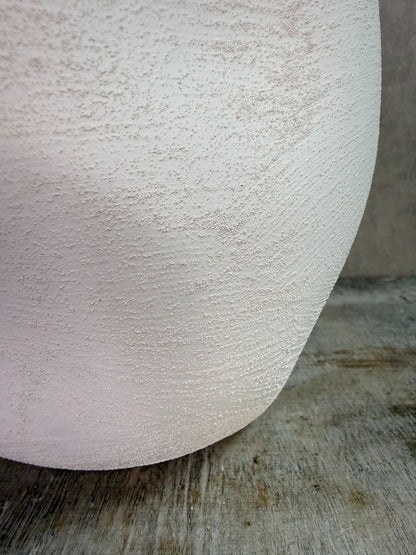 Witte keramieken plantenpot met ronde vorm en matte afwerking op een houten ondergrond.