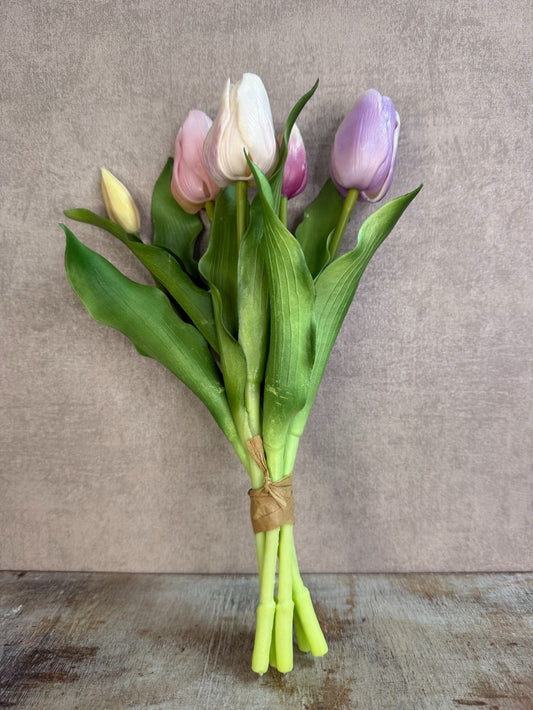 Bos real touch tulpen in zachte pasteltinten met groene bladeren, staand op een houten ondergrond tegen een neutrale achtergrond.