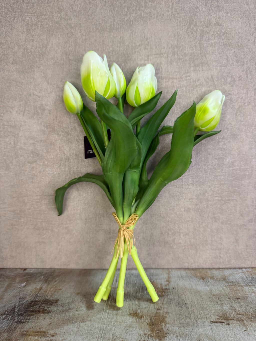 Bos real touch tulpen in wit met groene bladeren, samengebonden en geplaatst tegen een neutrale achtergrond.