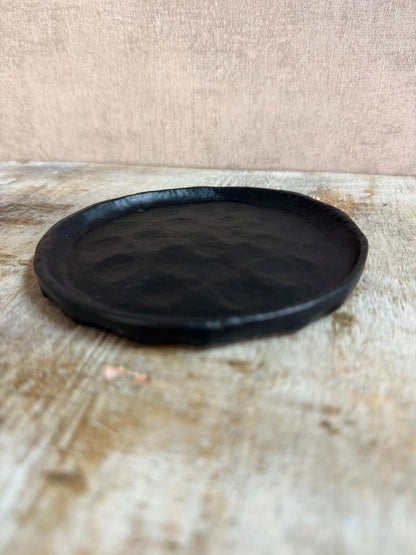 Rond zwart metalen schaaltje Forley met subtiel oneffen oppervlak, geplaatst op een houten ondergrond.