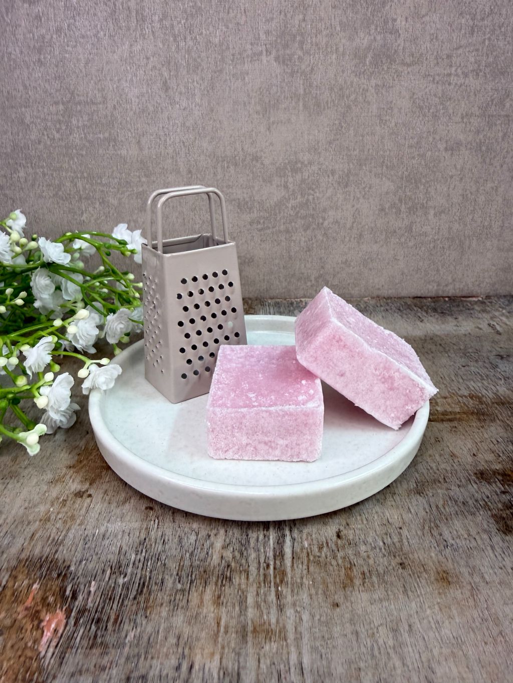 Wit keramieken schaaltje met  accessoires op een houten ondergrond tegen een neutrale achtergrond.