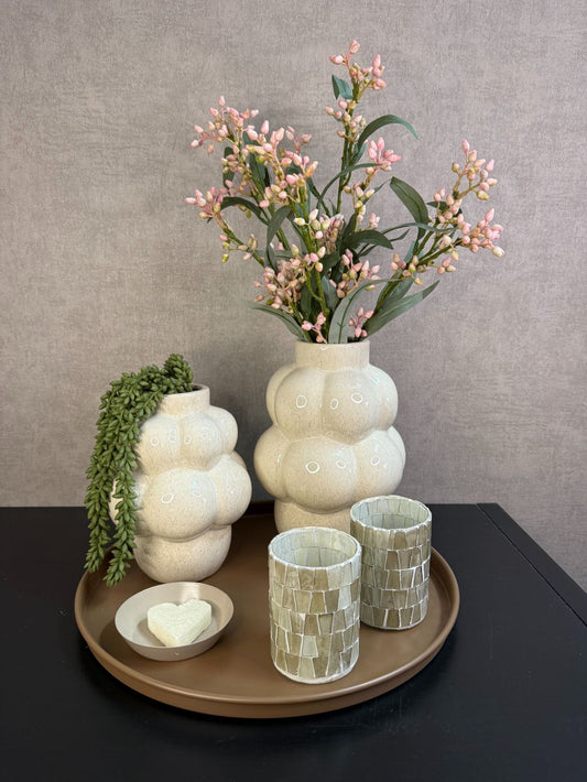 Tafel decoratie set met bruin dienblad, crème vazen, roze bloesemtakken, waxinelichthouders en amberblokje.