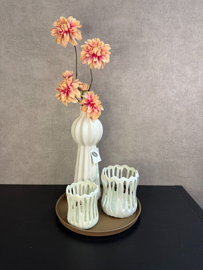 Tafel decoratie set met zalmkleurige dahlia’s, crème accessoires en bruin rond dienblad, stijlvol gepresenteerd op een tafel.