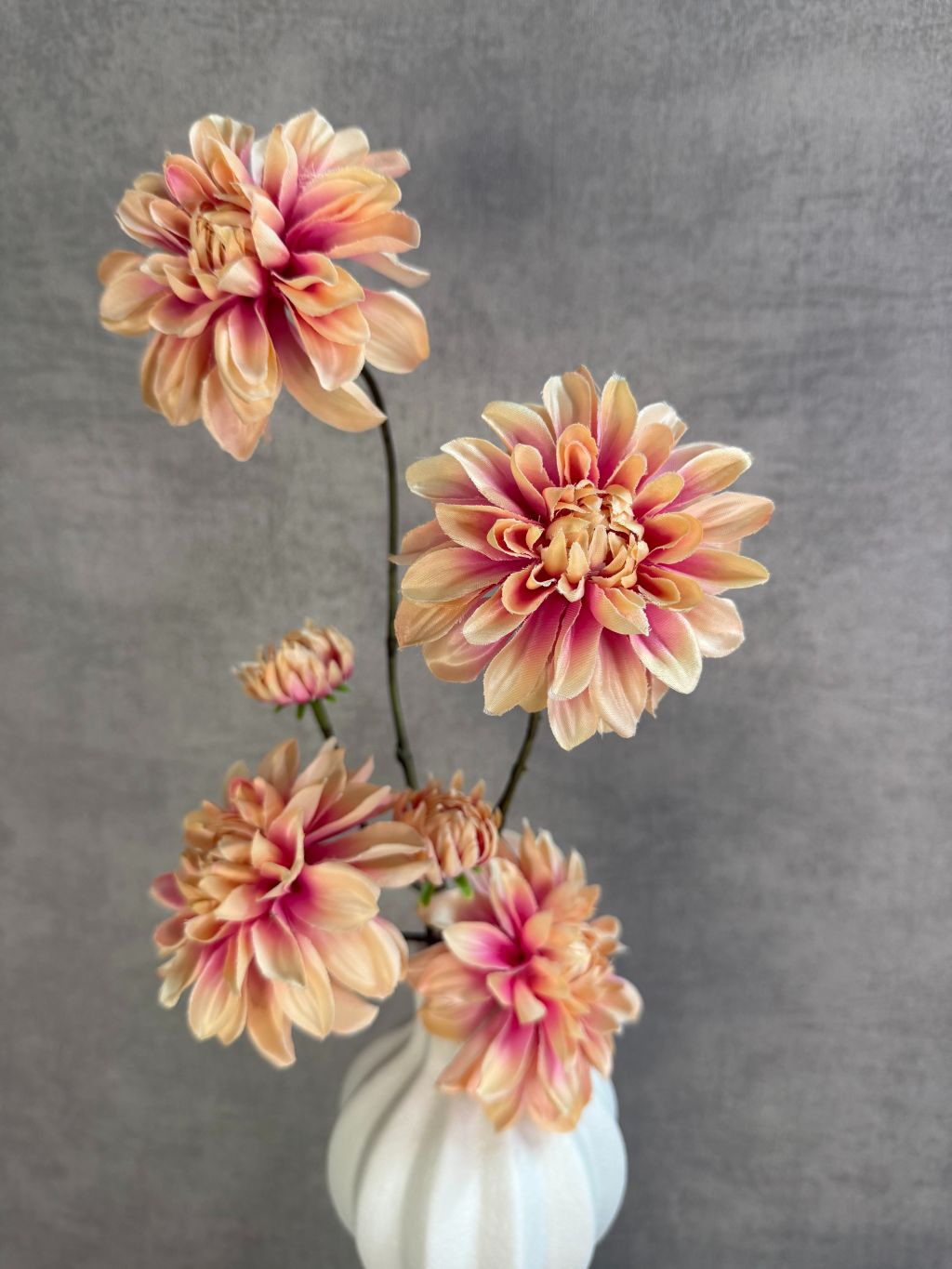 Tafel decoratie set met zalmkleurige dahlia’s, crème accessoires en bruin rond dienblad, stijlvol gepresenteerd op een tafel.