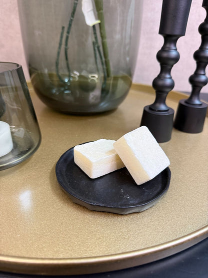 Goudkleurig dienblad met vaas met witte hortensia’s en eucalyptus, zwarte kandelaars, glazen waxinelichthouders en amberblokjes.