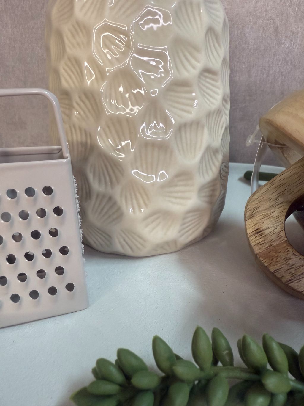 Tafel decoratieset met beige keramische houder, houten decoratie, amberblokje en groen takje op ovaal dienblad.