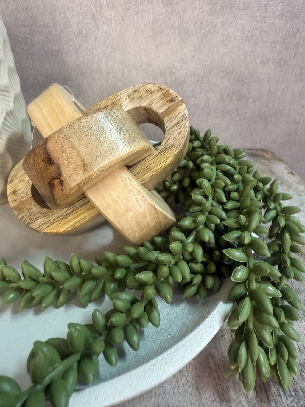 Tafel decoratieset met beige keramische houder, houten decoratie, amberblokje en groen takje op ovaal dienblad.