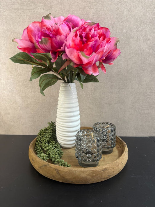 Decoratieset met roze pioenrozen in witte vaas op houten dienblad, aangevuld met zwarte theelichthouders en een groene kunst erwtenplant