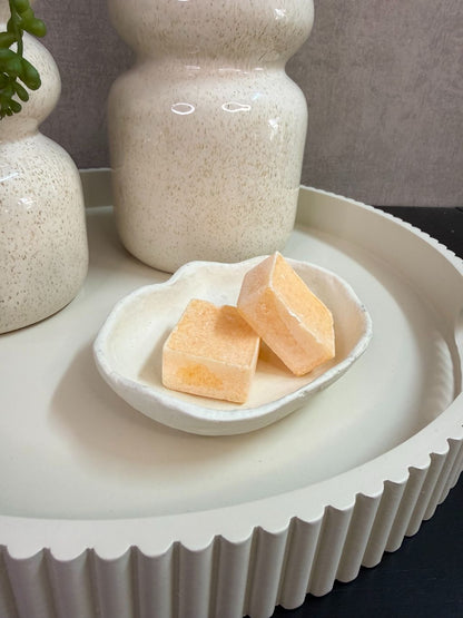 Tafel decoratie set met crèmekleurige vazen, paarse bloemen, groene hangplant en amberblokjes op een rond dienblad.