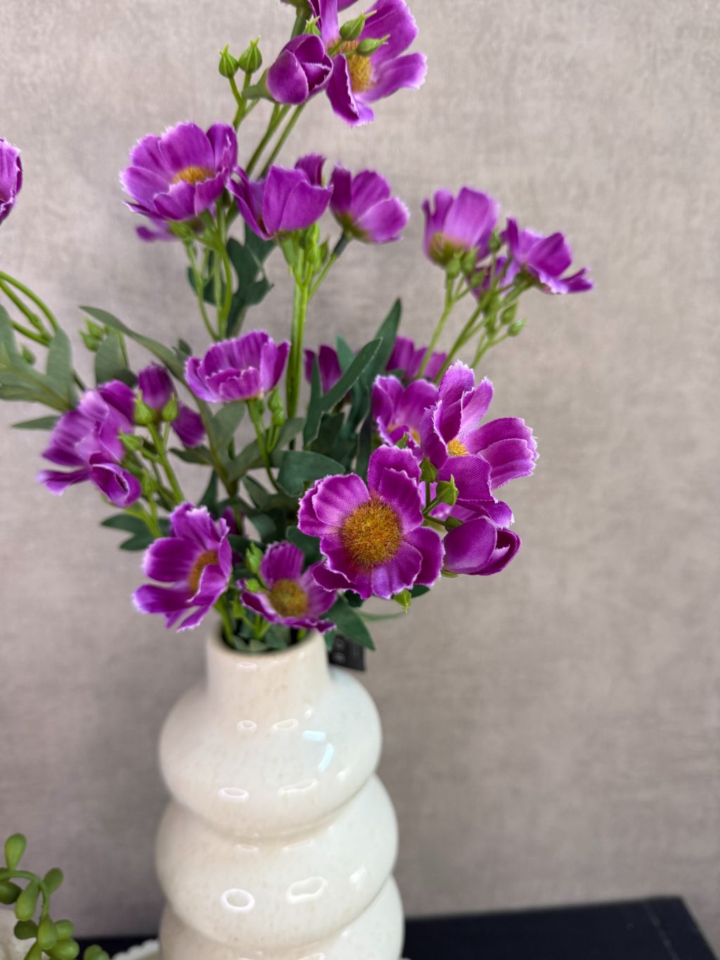 Tafel decoratie set met crèmekleurige vazen, paarse bloemen, groene hangplant en amberblokjes op een rond dienblad.