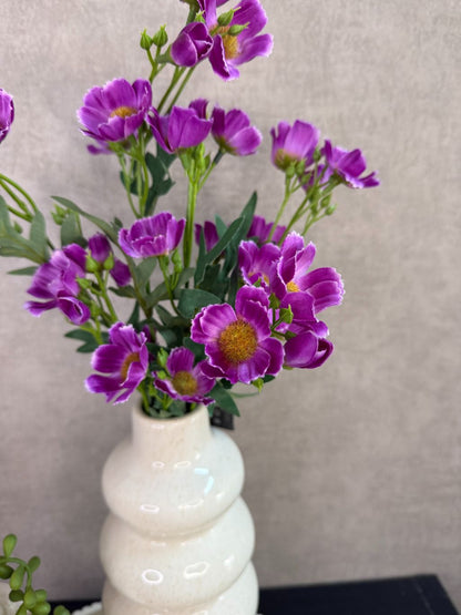 Tafel decoratie set met crèmekleurige vazen, paarse bloemen, groene hangplant en amberblokjes op een rond dienblad.