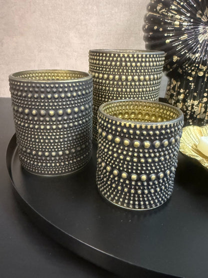 Tafel decoratie set Nelle – zwarte vaas met witte bloemen, goudkleurige schaal met amberblokjes en zwarte waxinelichthouders op rond dienblad.