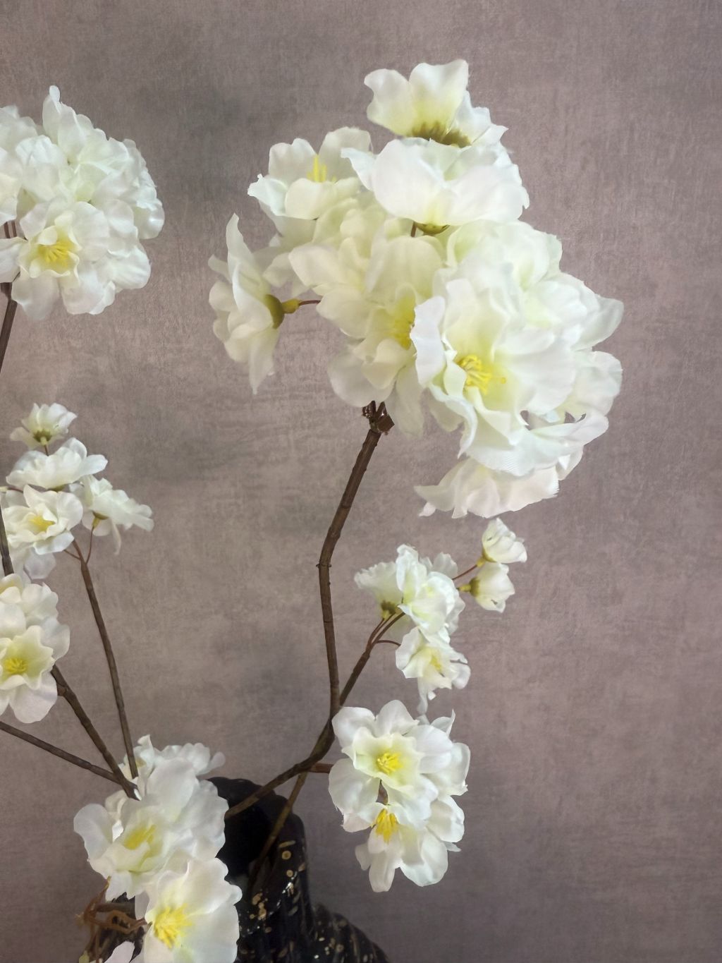 Tafel decoratie set Nelle – zwarte vaas met witte bloemen, goudkleurige schaal met amberblokjes en zwarte waxinelichthouders op rond dienblad.