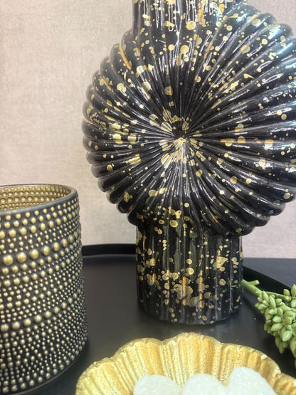 Tafel decoratie set Nelle – zwarte vaas met witte bloemen, goudkleurige schaal met amberblokjes en zwarte waxinelichthouders op rond dienblad.