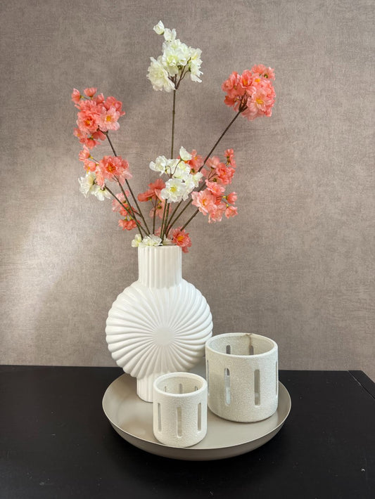 Tafeldecoratieset met witte vaas, zandkleurig dienblad, twee waxinelichthouders en kunsttakken met perzikroze en witte bloesems.
