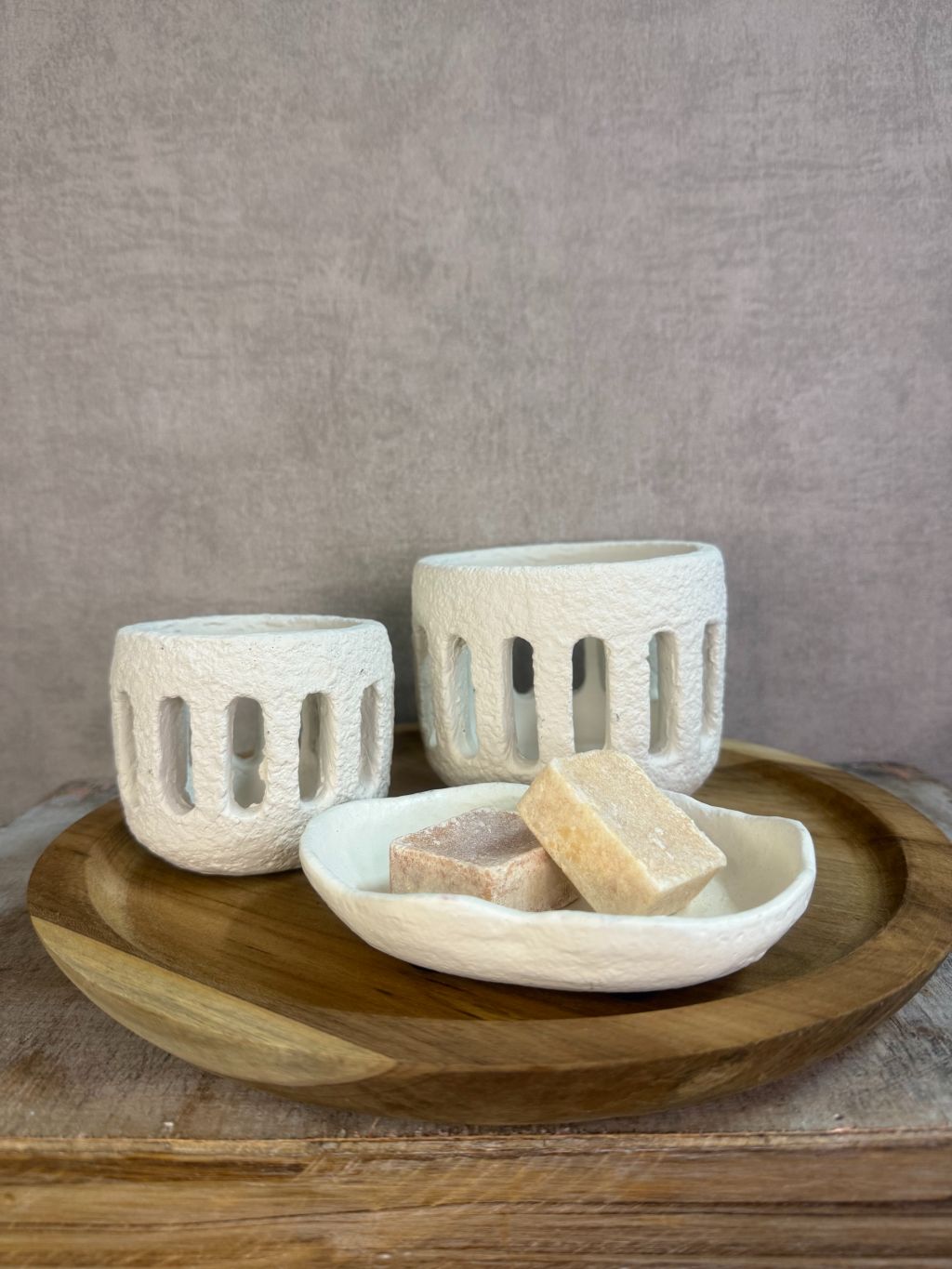 Rustieke tafeldecoratieset met houten dienblad, witte houders en amberblokjes op een houten ondergrond.