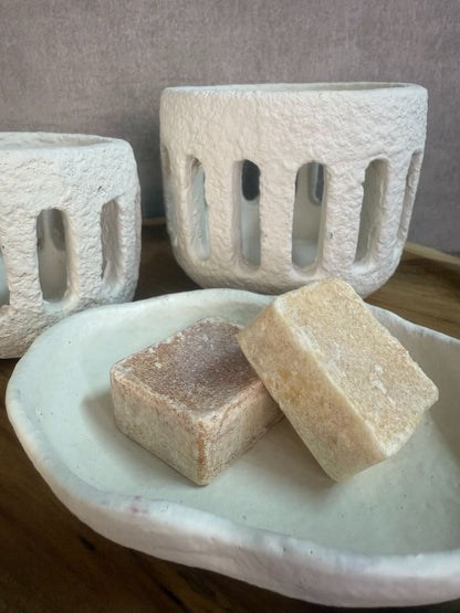 Rustieke tafeldecoratieset met houten dienblad, witte houders en amberblokjes op een houten ondergrond.