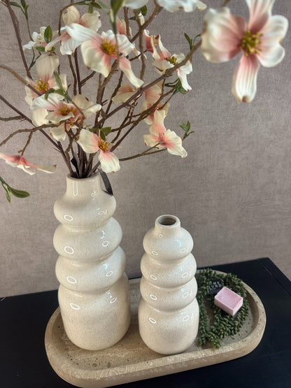 Tafeldecoratieset met beige vazen, bloeiende roze-witte takken, amberblokje en kunstplantje op marmerlook dienblad.