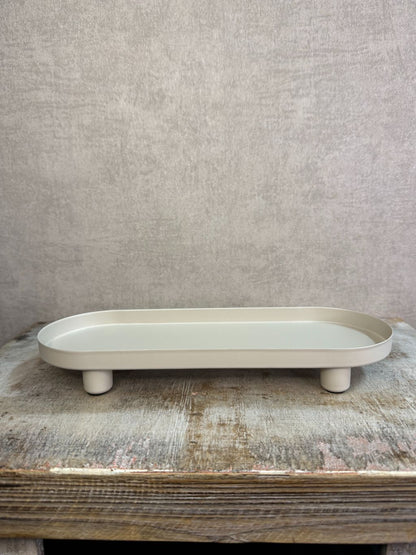 Beige metalen tray met een langwerpig ontwerp en lage rand, geplaatst op een houten ondergrond tegen een neutrale achtergrond.