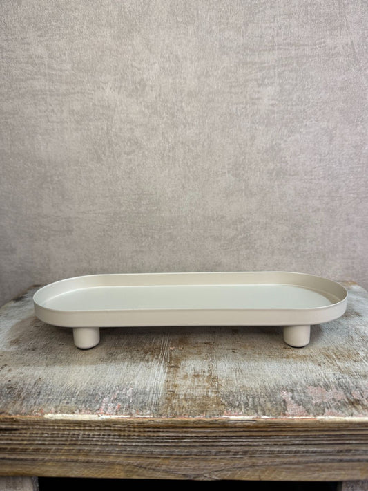 Beige metalen tray met een langwerpig ontwerp en lage rand, geplaatst op een houten ondergrond tegen een neutrale achtergrond.