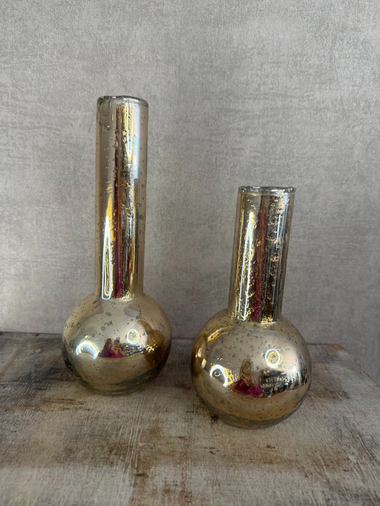 Twee gouden glazen vaasjes met bolle onderkant en smalle hals op houten ondergrond, glanzend met reflecterend oppervlak.